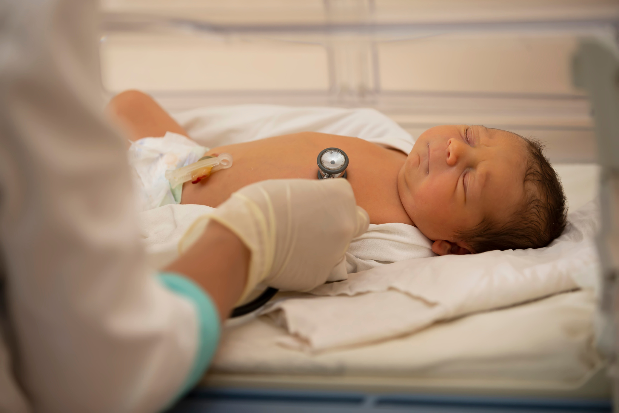 Neonatology. Doctor listening to the heartbeat of a newborn in an infant incubator